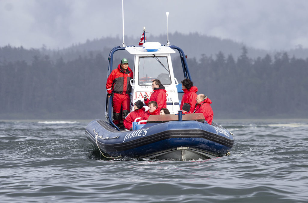 A zodiac with passengers wearing red vests.