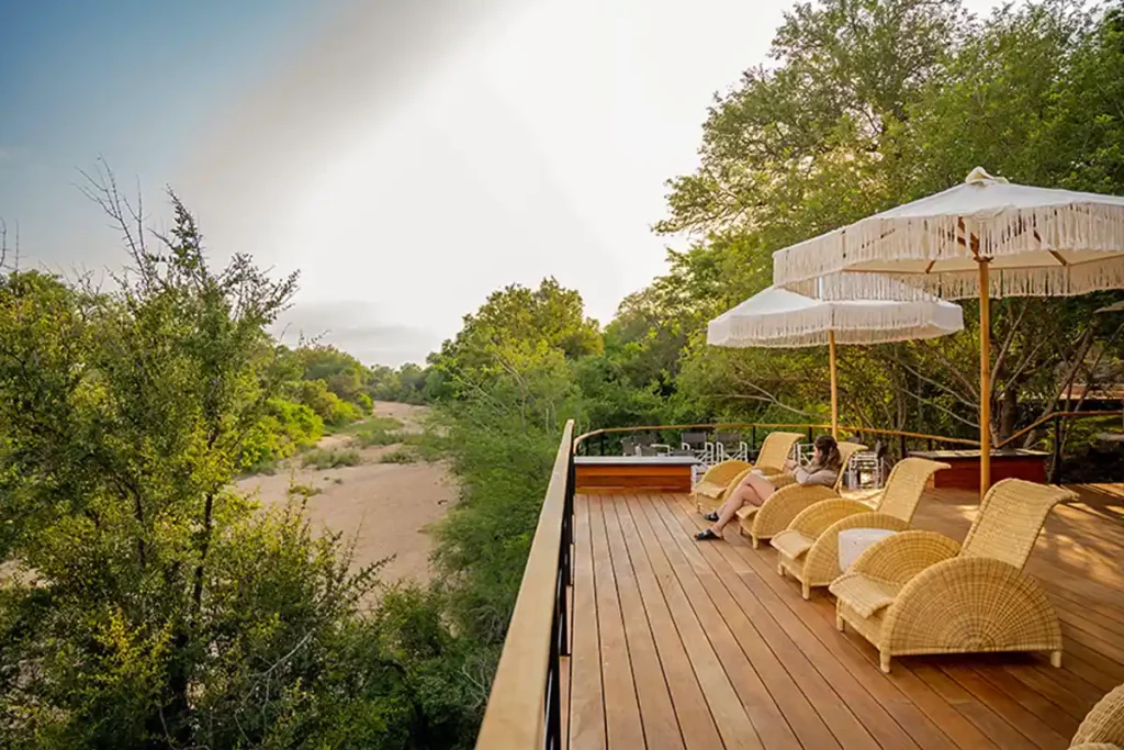 deck with chairs and a view to a dry riverbed at this lodge in kruger national park